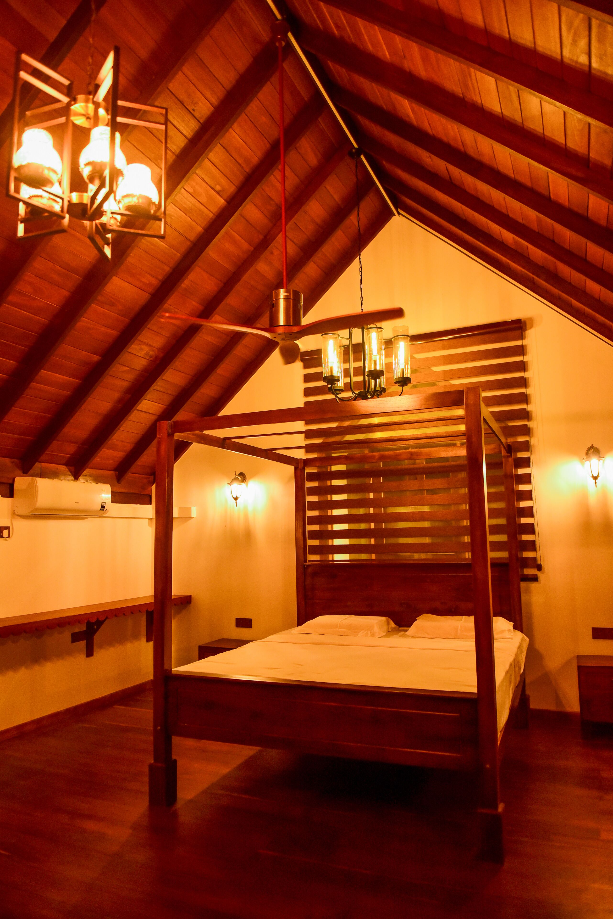 Une pièce aux hauts plafonds, avec un plafond en bois, un lit à baldaquin et un luminaire suspendu.
