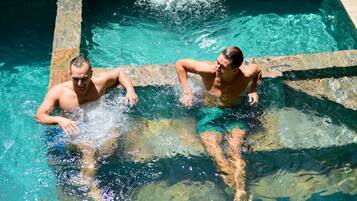 Due uomini in piscina, acqua cristallina e bordi in pietra.