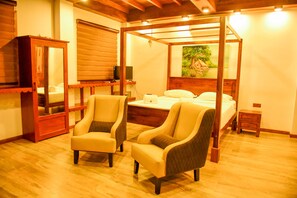 A bedroom with a four-poster bed, two armchairs, a wooden cabinet, and a painting on the wall. - Cara White House (Galle)