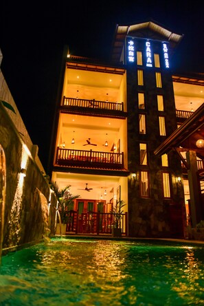 A multi-story hotel with a swimming pool in front. - Cara White House (Galle)