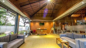 Un hallo espacioso con techo de madera, una recepción, sofás y un amplio ventanal con vistas al exterior.