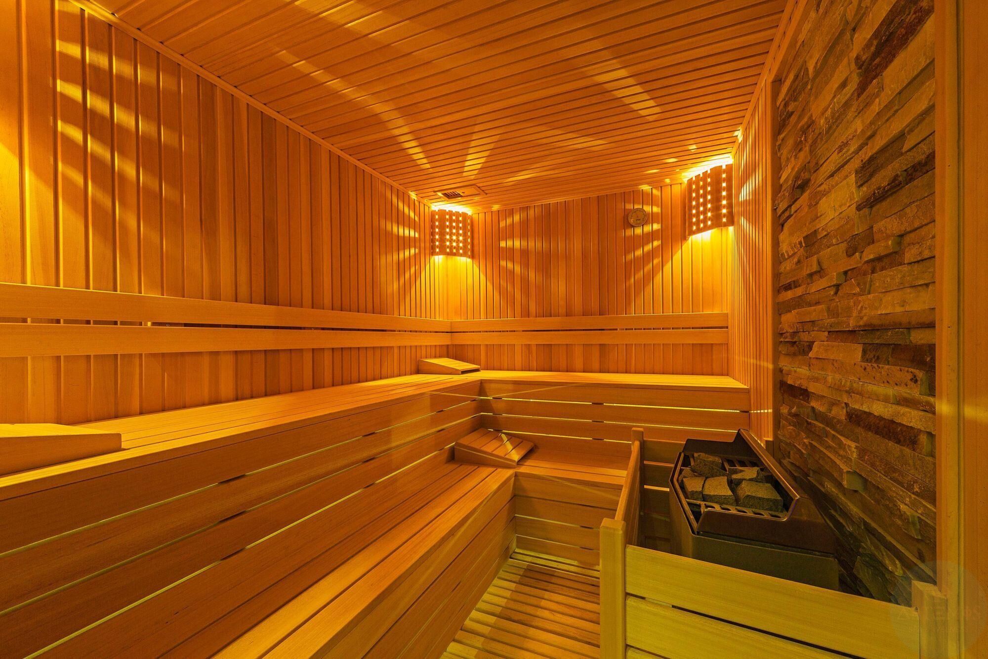 Eine Sauna mit Holzbänken und einer Steinwand.