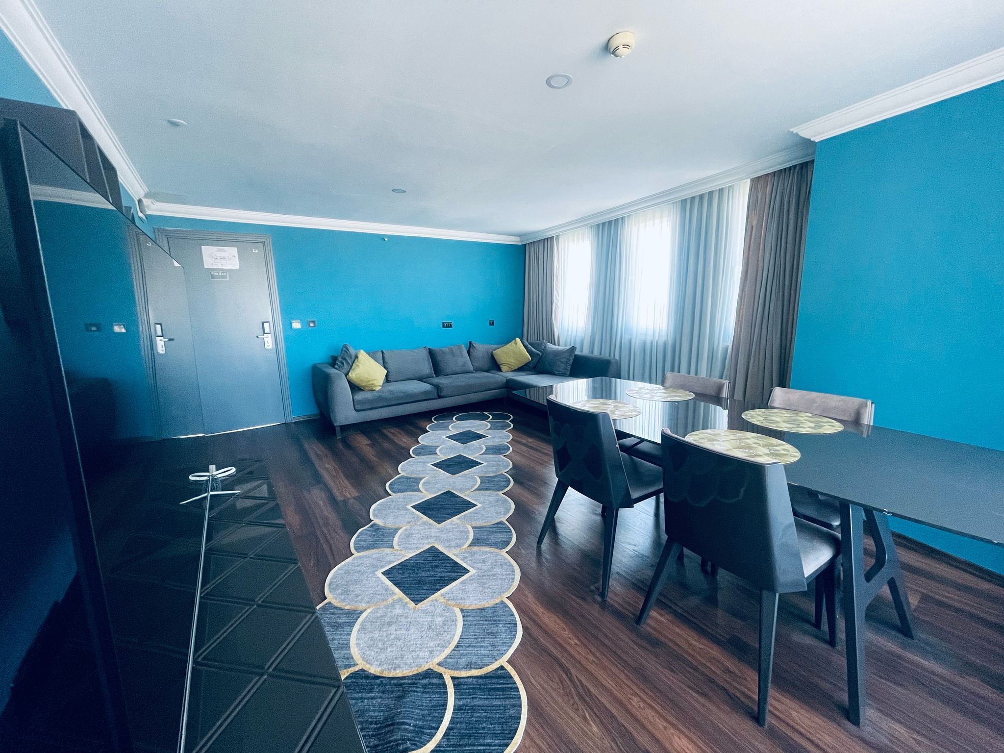Una sala de estar moderna con un sofá, una mesa de comedor con sillas y una alfombra estampada.