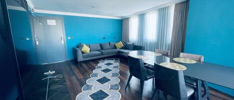 Una sala de estar moderna con un sofá, una mesa de comedor con sillas y una alfombra estampada.