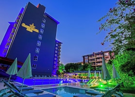Un hotel con piscina, sillas de descanso y sombrillas.
