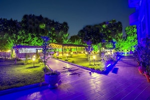 A well-lit outdoor area with a covered seating area, pathways, and potted plants.