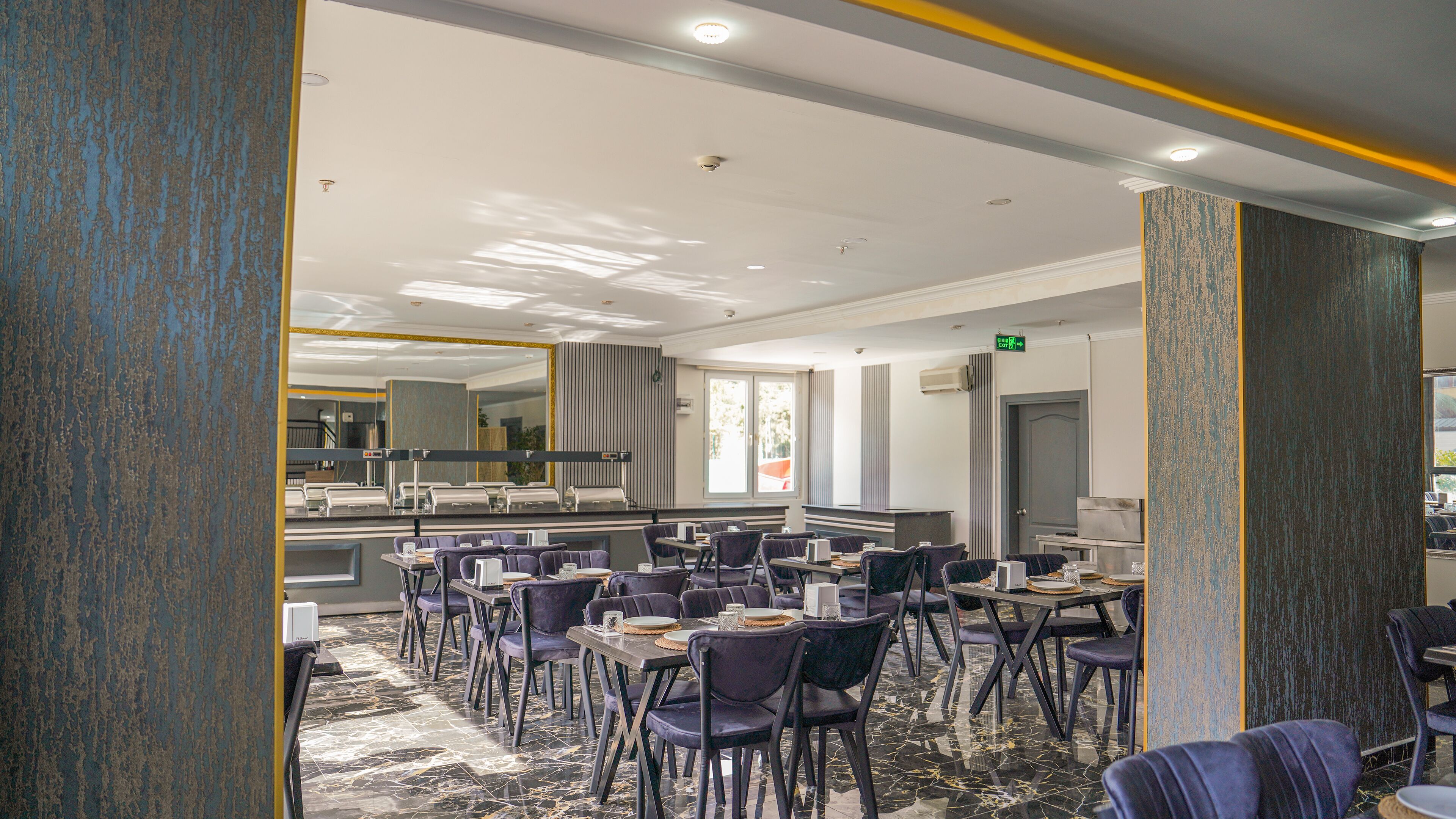 A modern dining area with marble flooring, dark upholstered chairs, and a central island with a sink.