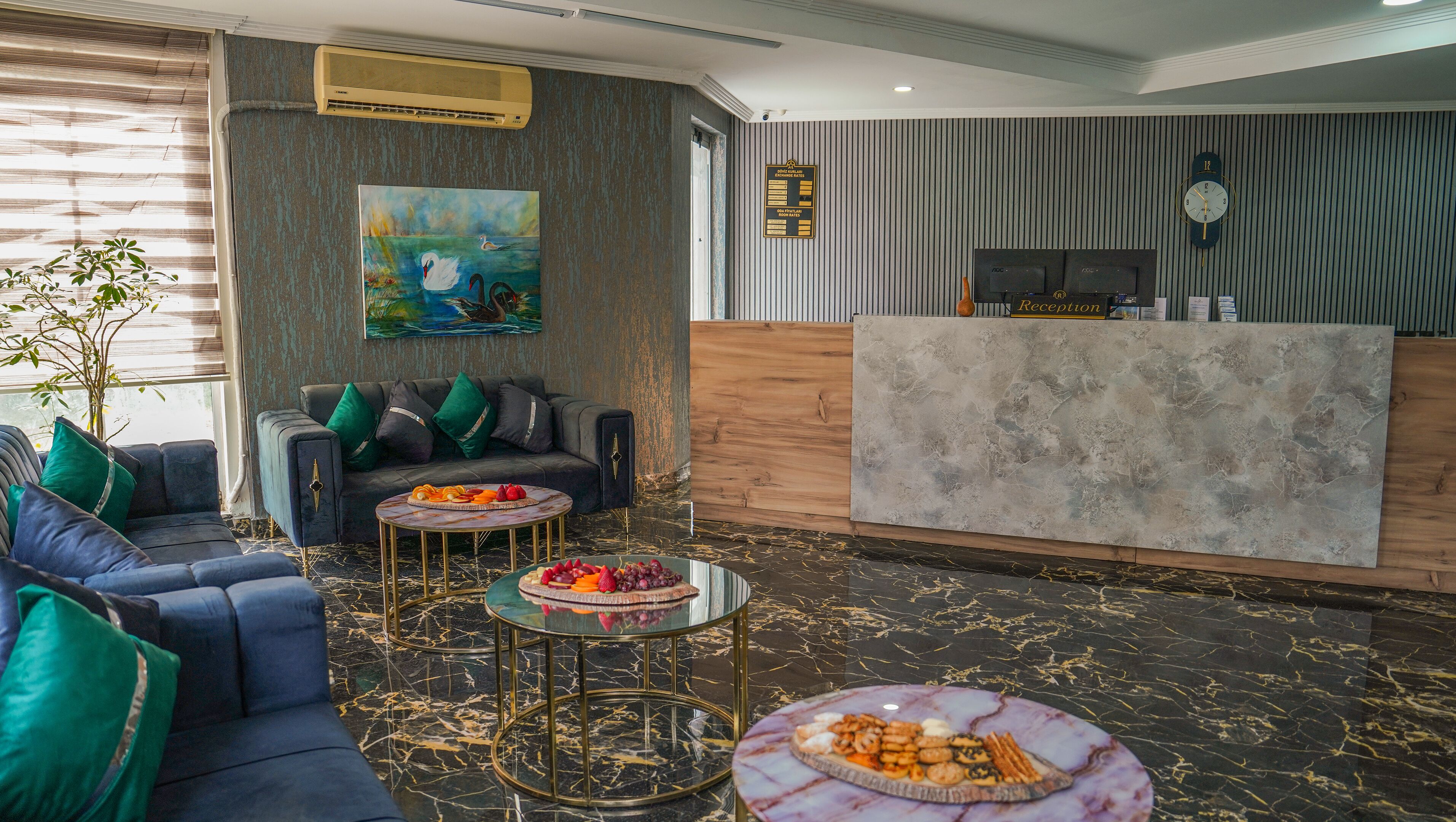 Un área de recepción moderna con piso de mármol, mostrador de recepción, un sofá y dos mesas auxiliares con fruta.