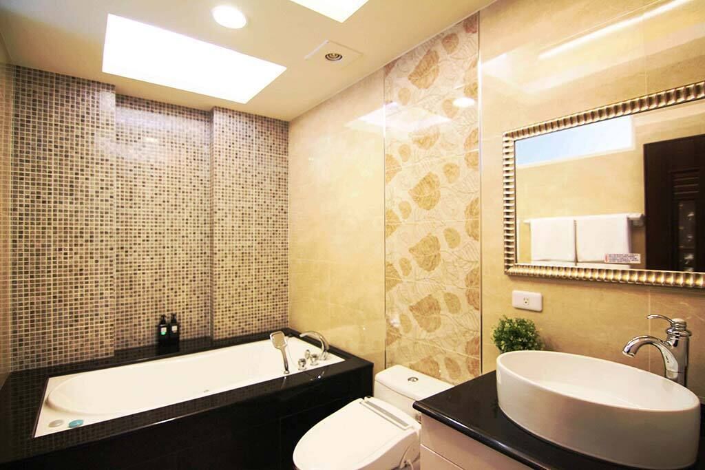 A modern bathroom with a black countertop, a white sink, and a large mirror.