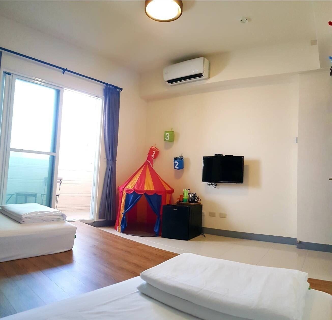Habitación de hotel con dos camas, televisión, aire acondicionado y una tienda de juegos.