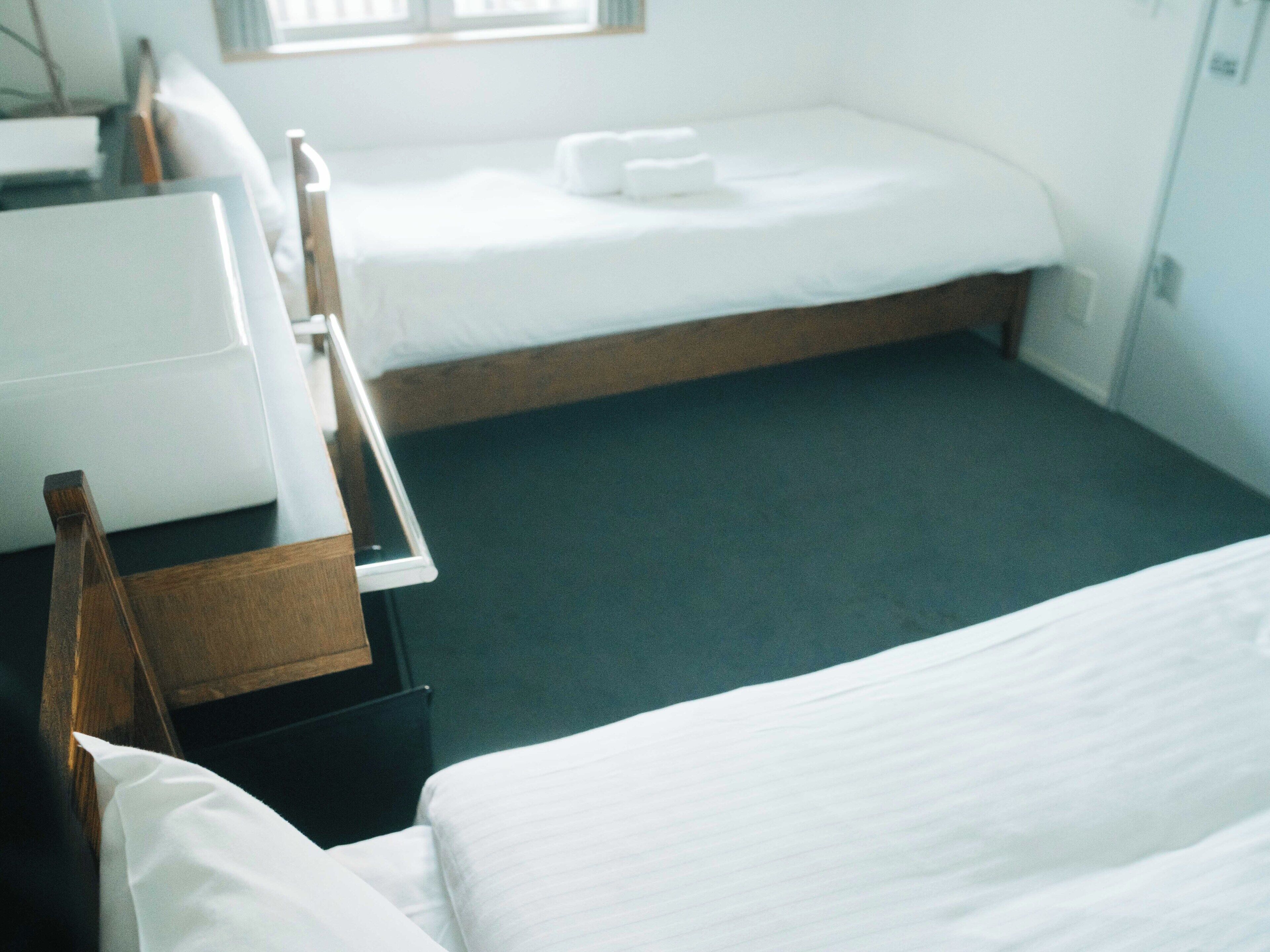 A hotel room with two beds, a desk, and a chair.