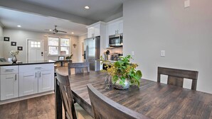 A modern kitchen with white cabinets, stainless steel appliances, and a wooden dining table with chairs. - Chic Atlanta Home < 4 Mi to Mercedes-Benz Stadium! (Atlanta)