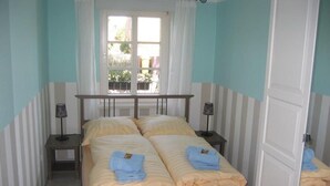 A double bed with two bedside tables, a window with curtains, and a door. - Green area 33 flat 7 (Wyk auf Föhr)