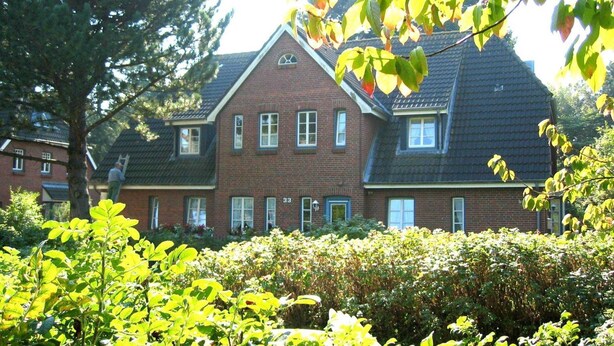 A two-story brick house with a gabled roof and multiple windows. - Green area 33 flat 7 (Wyk auf Föhr)