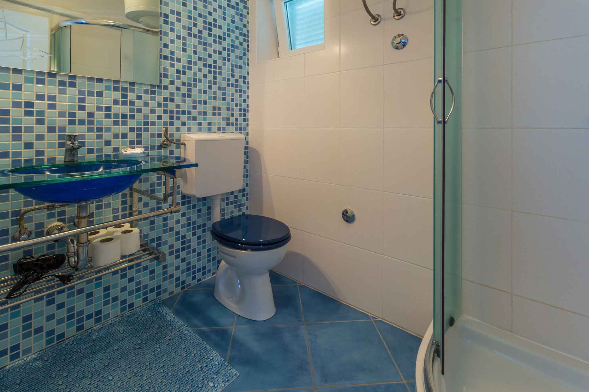 Et badeværelse med vask, toilet og brusebad.