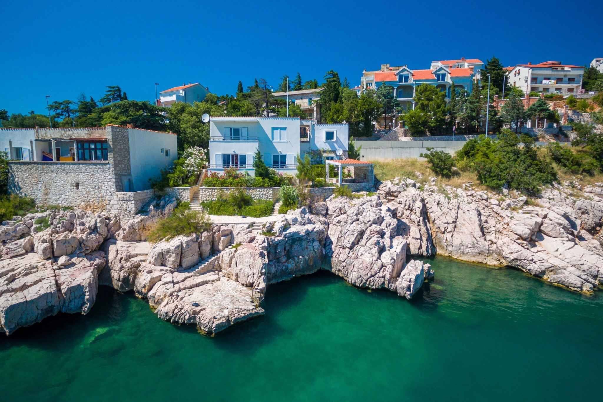 A coastal town with stone buildings, clear turquoise water, and a rocky shoreline.