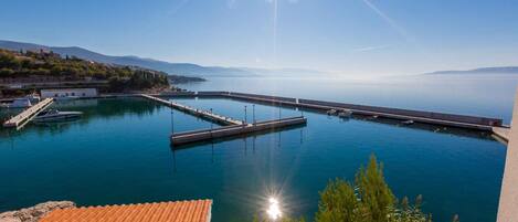Ein Yachthafen mit vertäuten Booten, eine Pier, die sich in ruhiges Wasser erstreckt, und ein klarer Himmel.