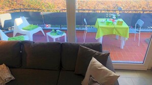 Un balcón con sofá, sillas y una mesa dispuesta para comer.
