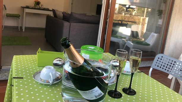 Una mesa de comedor con una botella de champán, copas y un mantel verde con lunares.