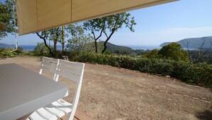 A table and chair under a canopy overlooking a scenic view of hills and a body of water.