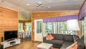 A cozy cabin interior with a wooden ceiling, a television, a sofa, and a dining area with chairs. - Vacation home Kaisla by Interhome (Heinola)