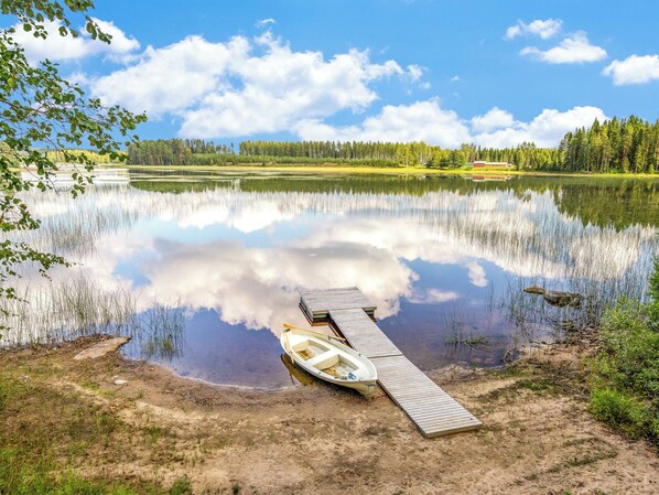 A calm lake with a wooden dock and a small boat.