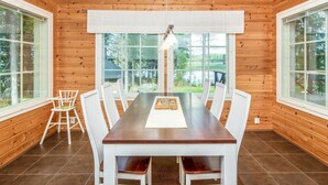 A wooden cabin with a dining table and chairs, large windows, and a view of the outdoors. - Vacation home Kaisla by Interhome (Heinola)