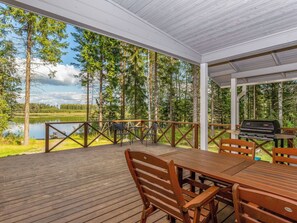 A covered outdoor deck with a table and chairs, overlooking a lake and forest. - Vacation home Kaisla by Interhome (Heinola)