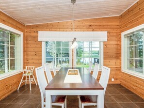 A wooden-paneled room with a large dining table, white chairs, and a view of the outdoors. - Vacation home Kaisla by Interhome (Heinola)