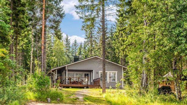 A cabin with a deck, surrounded by dense forest and a body of water. - Vacation home Kaisla by Interhome (Heinola)
