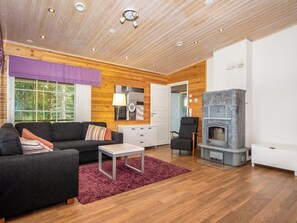 A modern living room with a sofa, a coffee table, a fireplace, and a view of the outdoors. - Vacation home Kaisla by Interhome (Heinola)