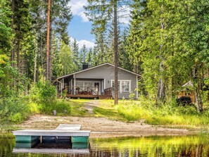 A cabin with a deck, surrounded by forest and a body of water. - Vacation home Kaisla by Interhome (Heinola)