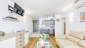 A modern living room with a glass coffee table, a beige sofa, and a TV mounted on a wall. - Port Salins by Interhome (Empuriabrava)