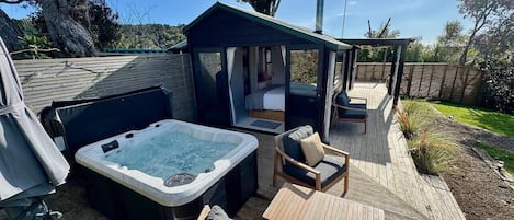 A hot tub, outdoor seating, and a covered area with a view of the surrounding landscape.