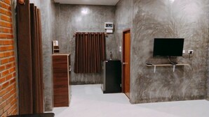 Een hotelkamer met een marmeren wand, een aan de wand bevestigde televisie, een houten kast en een gordijn.