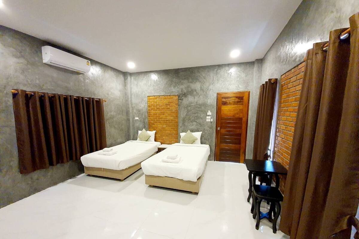 A hotel room with two beds, a small table, and a chair.