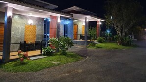 Een modern gebouw met een overdekt terras, een bakstenen muur en een verzorgde tuin.