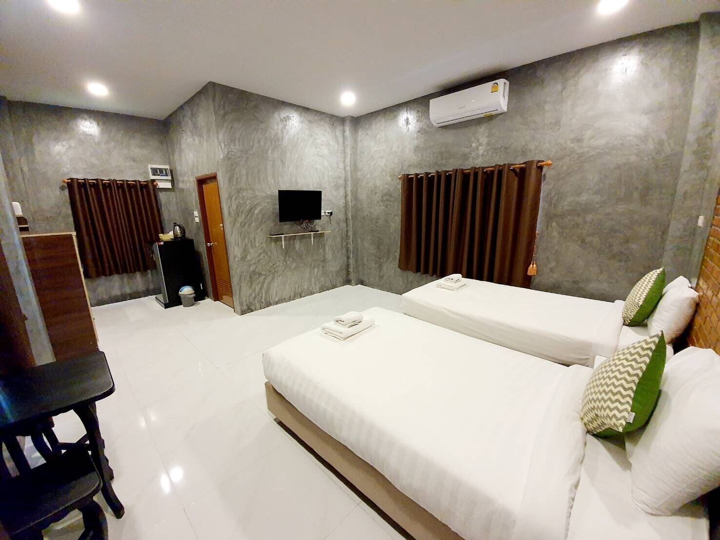 Habitación de hotel con dos camas, televisión, aire acondicionado y escritorio.