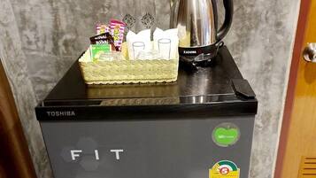 A compact refrigerator with a Toshiba logo, a direct cool sticker, and a few items on top including a bottle, a box, and a kettle.