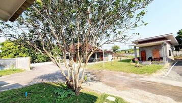 Zona residencial con una casa, un árbol y un camino de entrada pavimentado.