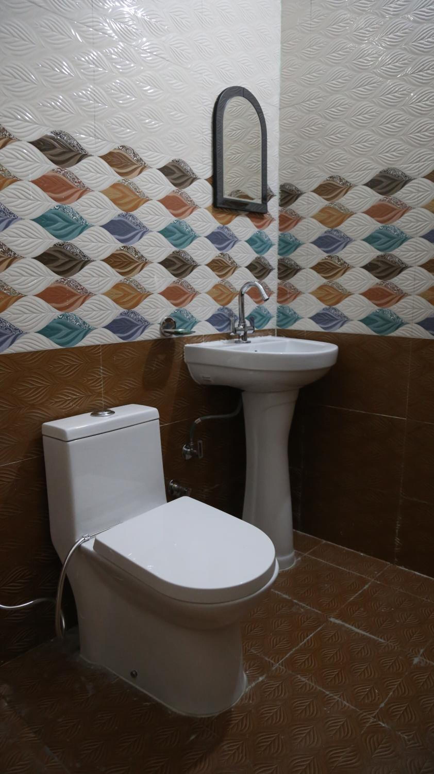 A bathroom with a toilet, sink, and decorative patterned wall tiles.