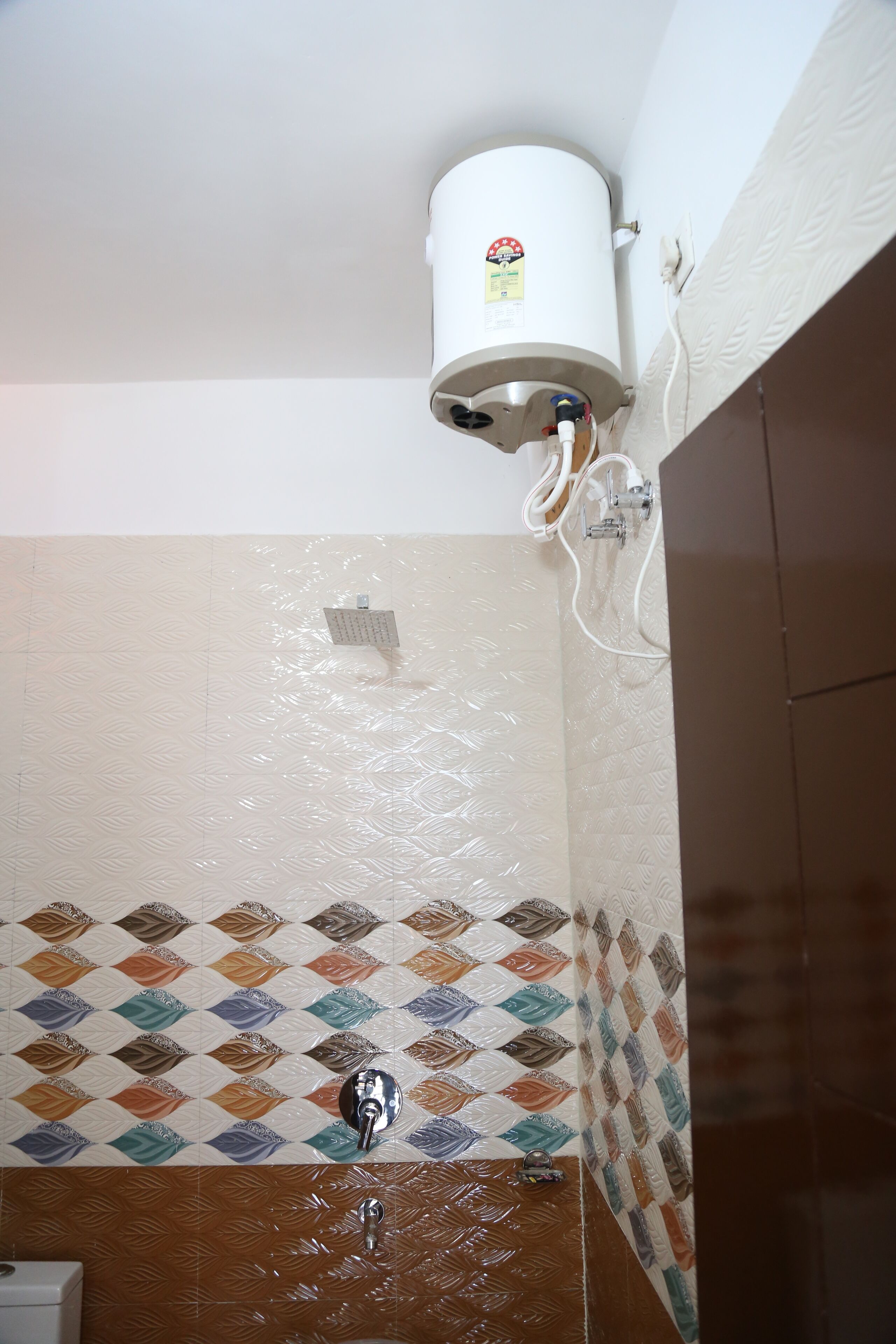 Ein Badezimmer mit weißem Duschkopf, Wandheizung und gemusterten Fliesen.