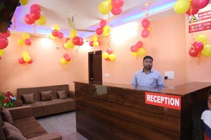 A reception area with a wooden reception desk labeled "RECEPTION," a brown sofa, and a ceiling fan.