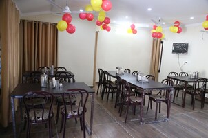 A dining area with multiple tables and chairs, ceiling fans, and balloons.
