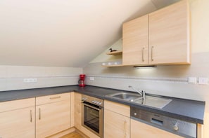 A kitchen with wooden cabinets, a built-in oven, a sink, and a coffee maker.