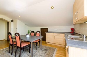 Una cocina compacta con comedor, armarios de madera, un lavamanos y una cafetera.