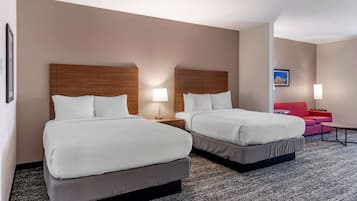 Una habitación de hotel con dos camas, un sofá rojo y una pequeña mesa.