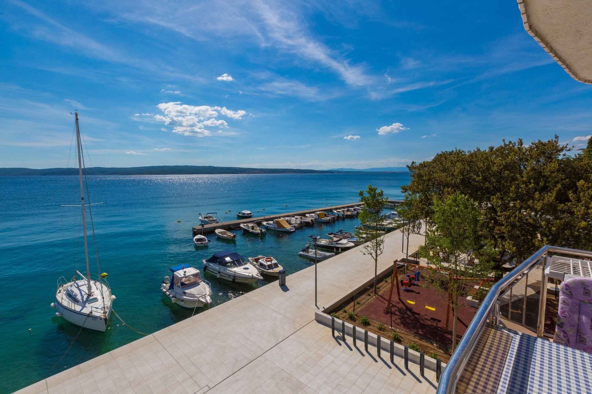 Ein Yachthafen mit angestaubten Booten, ein klarer, blauer Himmel und Blick aufs Meer.