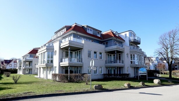 A multi-story residential building with balconies, a well-maintained lawn, and a clear sky. - Dünenblick apartment DBL02, house 1 (Ostseebad Boltenhagen)