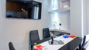 Une salle de réunion moderne équipée d’un téléviseur à écran plat, de fauteuils en cuir noir, d’une table en verre et d’étagères intégrées.